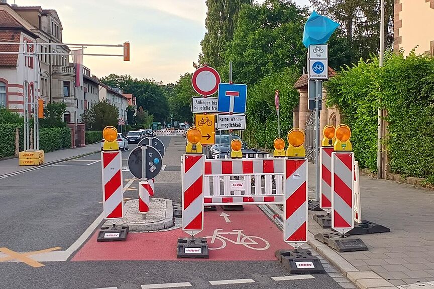 Erlangen Loewenichstrasse Im Vordergrund rechts viele Schilder und eine Baustellenabsperrung auf der Radspur.
